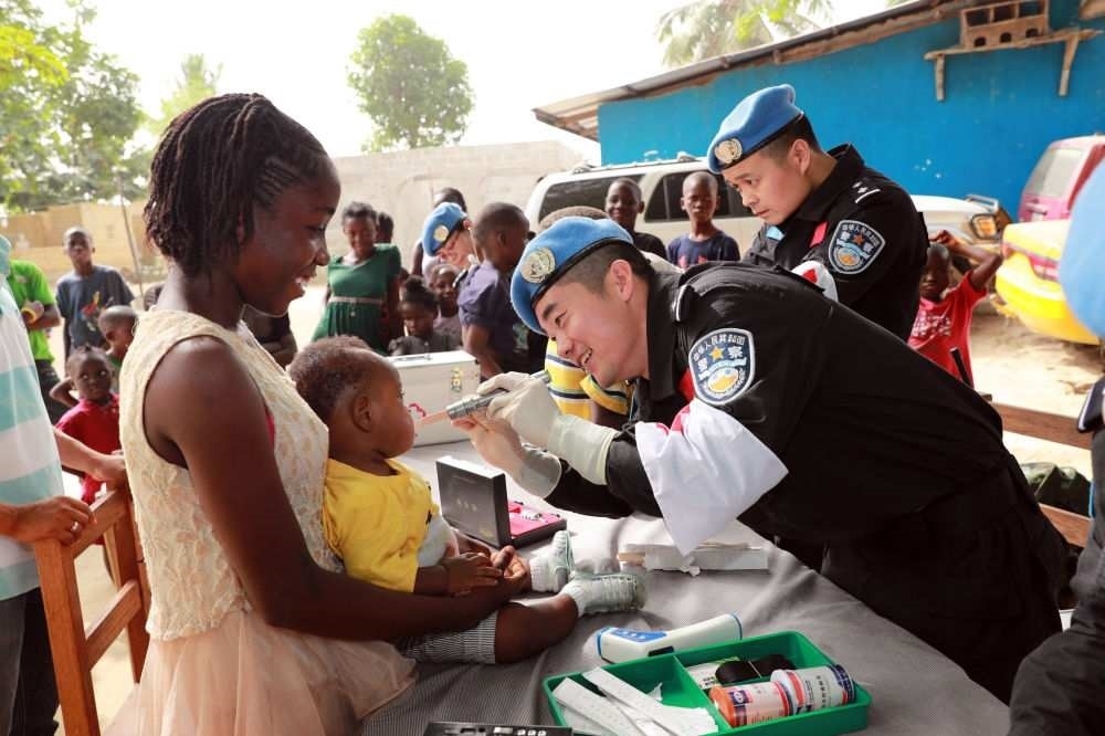 2017年12月28日，在利比里亞蒙羅維亞，中國維和警察防暴隊(duì)醫(yī)療人員為兒童做口腔檢查。