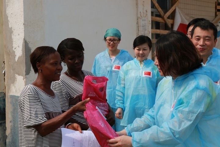 2015年4月4日，在位于塞拉利昂首都弗里敦市郊的中塞友好醫(yī)院埃博拉診療中心，中國(guó)第四批援塞醫(yī)療隊(duì)副隊(duì)長(zhǎng)邵蔚（右前）向被治愈的埃博拉出血熱患者贈(zèng)送禮物。新華社發(fā)（祖榮強(qiáng) 攝）
