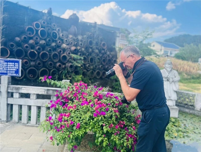 遠處黔北民居錯落有致，近處一只黑色的蝴蝶穿梭于粉紫色三角梅花叢間隙，與俄羅斯“大歐亞”總編輯弗拉基米爾·別列日內赫的鏡頭玩起了捉迷藏，“你追我逃，不亦樂乎”。（張亞欣攝）