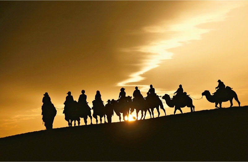 新時代以來，文化和旅游深度融合發(fā)展體制機(jī)制不斷健全，成功走出了一條獨(dú)具特色的中國旅游發(fā)展之路。圖為2024年9月1日清晨，游客在甘肅省敦煌市鳴沙山月牙泉景區(qū)乘騎駱駝，欣賞大漠風(fēng)光，體驗(yàn)絲路風(fēng)情。 新華社發(fā) 張曉亮/攝