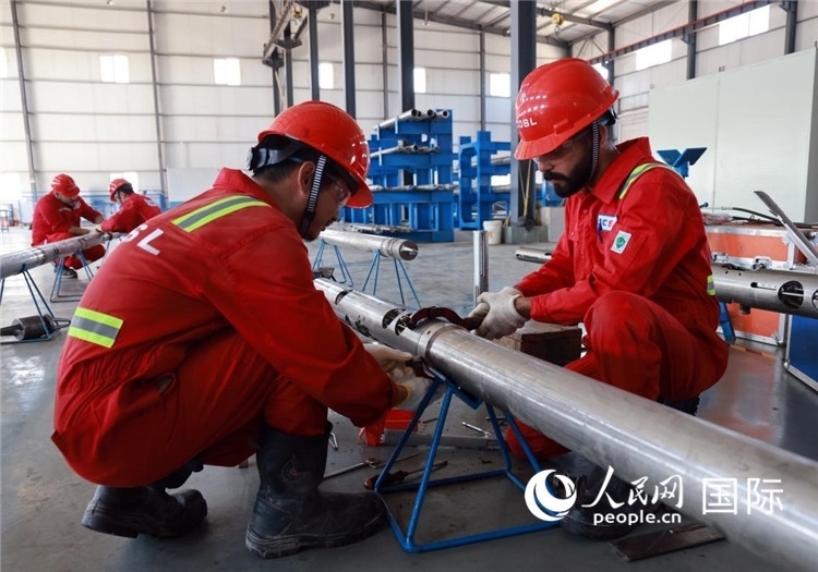 中伊員工共同在檢修鉆井設(shè)備。人民網(wǎng)記者管克江攝