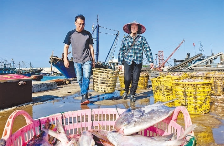 許小斌（左）和漁民一起搬運海鮮。本報記者 付 文攝