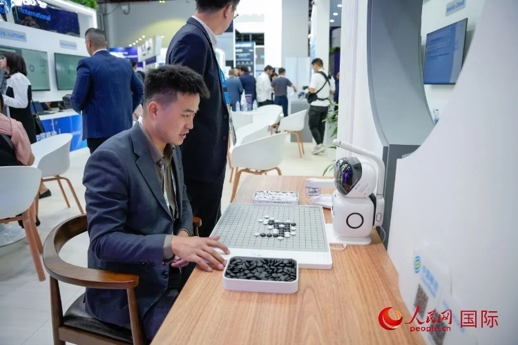 觀眾在中國移動國際有限公司展臺體驗(yàn)智慧圍棋機(jī)器人。人民網(wǎng) 塔里克·易卜拉欣攝