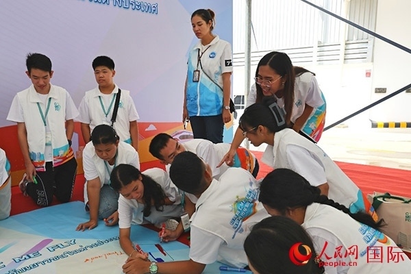 泰國學生在開營儀式展板上繪制圖案。人民網(wǎng)記者 白元琪攝