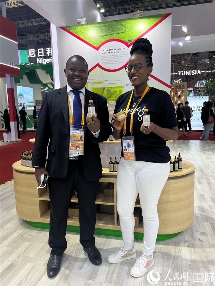 6月6日，布隆迪駐華大使館一等參贊布利馬索·阿爾弗雷德 (左，Bulimaso Alfred) 和參展商卡馬里扎·埃斯特拉 (Kamariza Estella) 在第七屆中國國際進(jìn)口博覽會布隆迪館展示當(dāng)?shù)厣a(chǎn)的辣木油。（人民網(wǎng) 艾里士 攝）