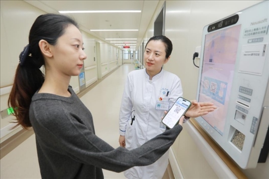 醫(yī)護人員引導患者在自助機前辦理自助入院手續(xù)。圖片來源：山東第一醫(yī)科大學第二附屬醫(yī)院