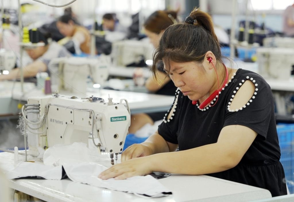 5月20日，村民在李寨村服裝加工廠內(nèi)忙碌。河南省周口市沈丘縣馮營鎮(zhèn)李寨村地處豫東平原。近年來，乘著脫貧攻堅與鄉(xiāng)村振興政策的東風，李寨村積極探索產(chǎn)業(yè)發(fā)展模式，通過“龍頭企業(yè)+村集體經(jīng)濟+農(nóng)戶”的方式，逐漸發(fā)展形成肉牛養(yǎng)殖、設(shè)施農(nóng)業(yè)、服裝加工、康養(yǎng)民宿等產(chǎn)業(yè)，以產(chǎn)業(yè)振興助力鄉(xiāng)村振興。新華社記者 李嘉南 攝