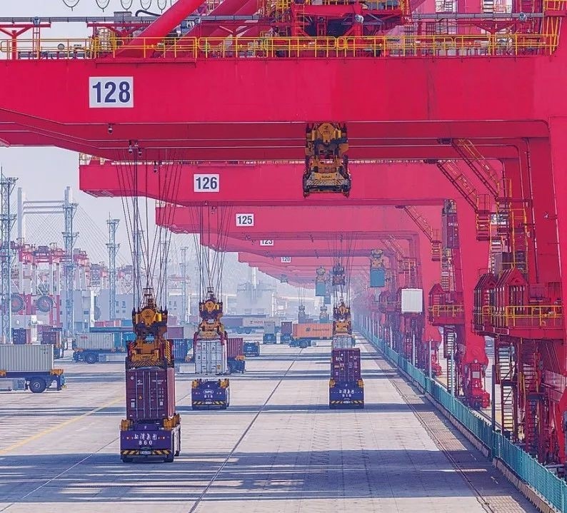 共建“一帶一路”國家在工作制度對接、技術(shù)標準協(xié)調(diào)、檢驗結(jié)果互認等方面強化合作、統(tǒng)一標準，貿(mào)易自由化便利化水平不斷提升。上海洋山港海關(guān)對接共建國家進出口貨物相關(guān)標準，推動通關(guān)一體化方式申報，提升通關(guān)效率。圖為無人駕駛的全自動導(dǎo)引車在洋山港穿梭往來，搬運集裝箱。王初 攝