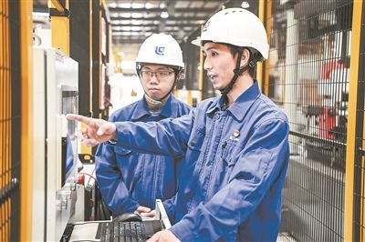 在廣西柳工機械股份有限公司生產(chǎn)車間內(nèi)，一名高級技師（右）給徒弟講解數(shù)控設(shè)備操作細節(jié)。新華社記者 曹祎銘攝