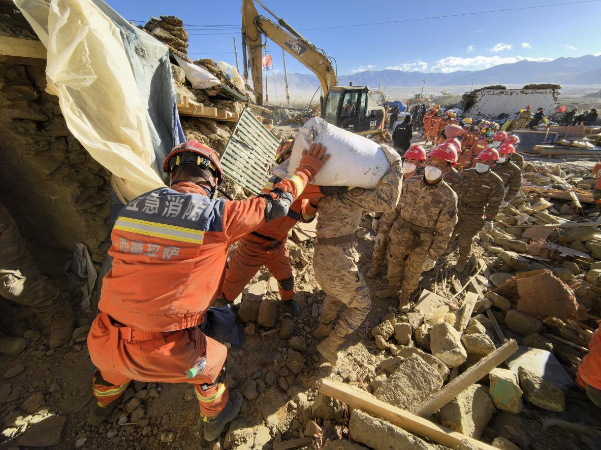 1月11日，定日縣長(zhǎng)所鄉(xiāng)古榮村，應(yīng)急消防等救援人員排隊(duì)接力搶運(yùn)掩埋在倒塌房屋下的群眾財(cái)物。人民日?qǐng)?bào)記者楊翹楚攝