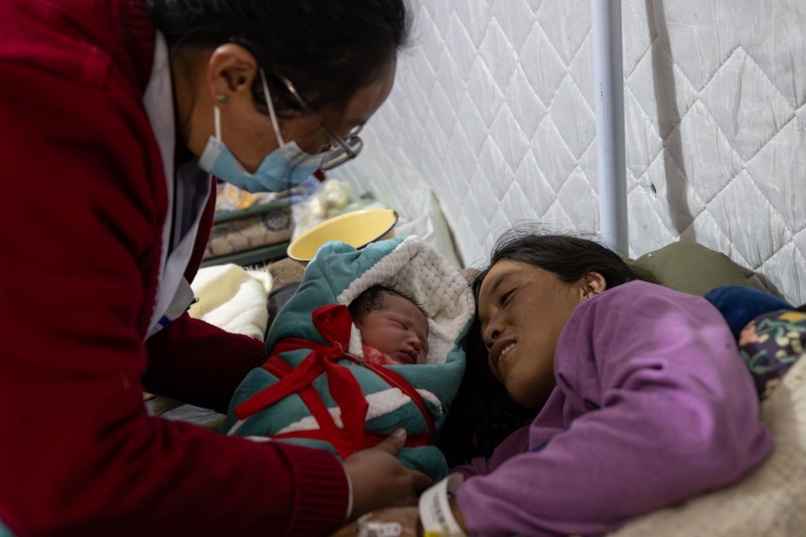 1月10日，定日縣中心醫(yī)院的婦產(chǎn)科醫(yī)生悉心照看一位母親和她懷里的新生兒。人民日?qǐng)?bào)記者張武軍攝