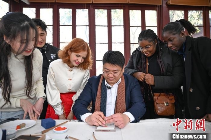 1月20日，篆刻家王臻向外籍留學(xué)生展示篆刻印章。當(dāng)日，來(lái)自巴西、馬來(lái)西亞、加納、哈薩克斯坦的外籍留學(xué)生在浙江杭州西泠印社體驗(yàn)福貼、春聯(lián)和篆刻，感受古老的中國(guó)傳統(tǒng)文化。中新社記者 王剛 攝