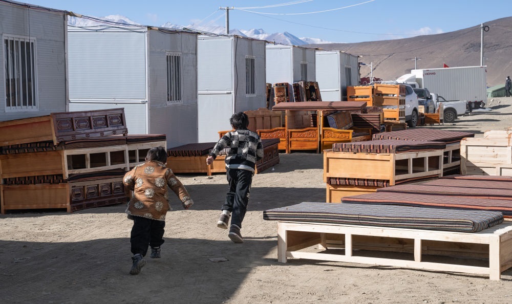 2025年1月13日，在定日縣嘎旦村，兩個孩子在剛運(yùn)來的兩排藏床間奔跑。新華社記者丁增尼達(dá) 攝