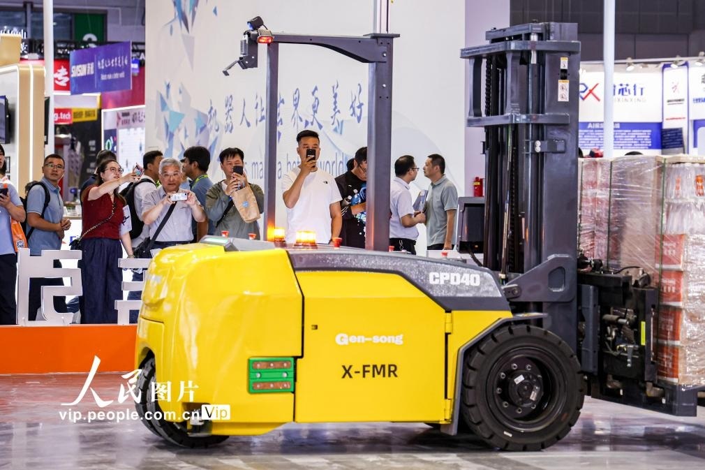 第24屆中國工博會現(xiàn)場，觀眾觀看叉取機(jī)器人作業(yè)演示。王初攝（人民圖片網(wǎng)）