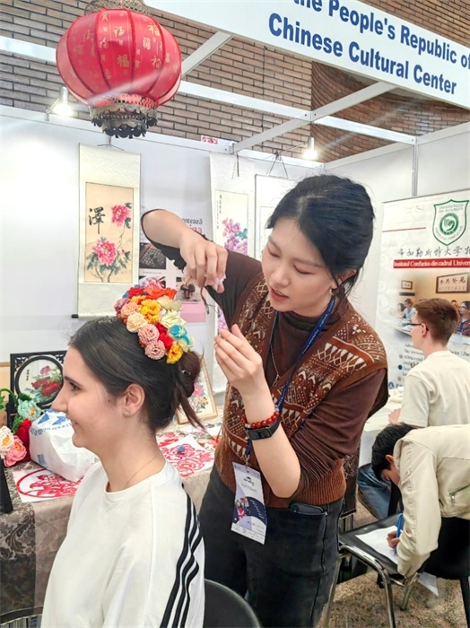 展覽正值羅馬尼亞迎春花節(jié)，國際中文教師志愿者潘婧穎向游客們介紹了國家非物質(zhì)文化遺產(chǎn)——福建泉州的簪花文化。布加勒斯特大學(xué)孔子學(xué)院供圖。