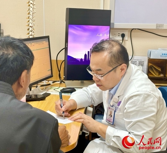 路桂軍接診時(shí)為患者寫下用藥提示。人民網(wǎng)記者 金慧慧攝