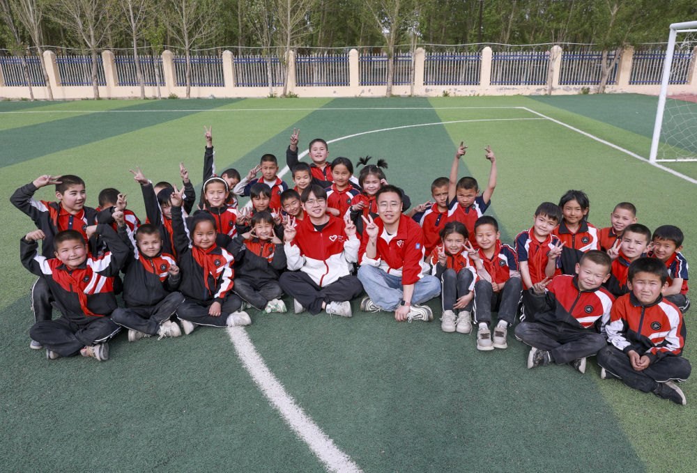 4月23日，在新疆克州阿圖什市哈拉峻鄉(xiāng)謝依特小學(xué)，支教教師王俊文（中左）、李軻凡（中右）和學(xué)生在一起。