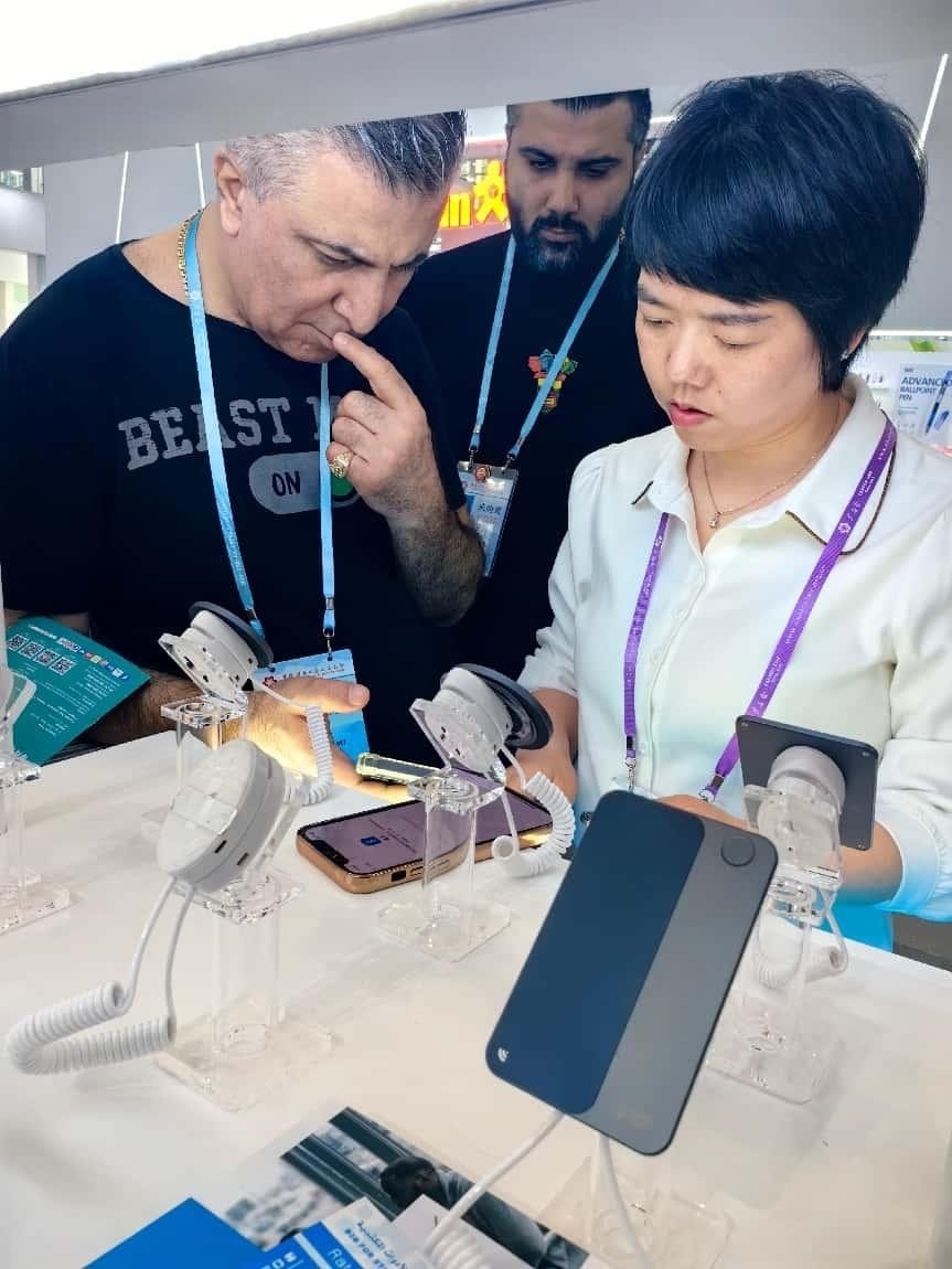展臺(tái)工作人員向外商展示“AI TOP翻譯終端”。圖片來源：受訪者提供