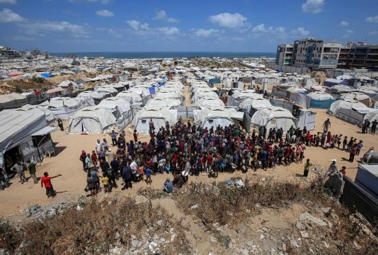 5月28日，人們?cè)诩由吵俏鞑康纳程犭y民營等待領(lǐng)取救助食物。新華社發(fā)（里澤克·阿卜杜勒賈瓦德攝）